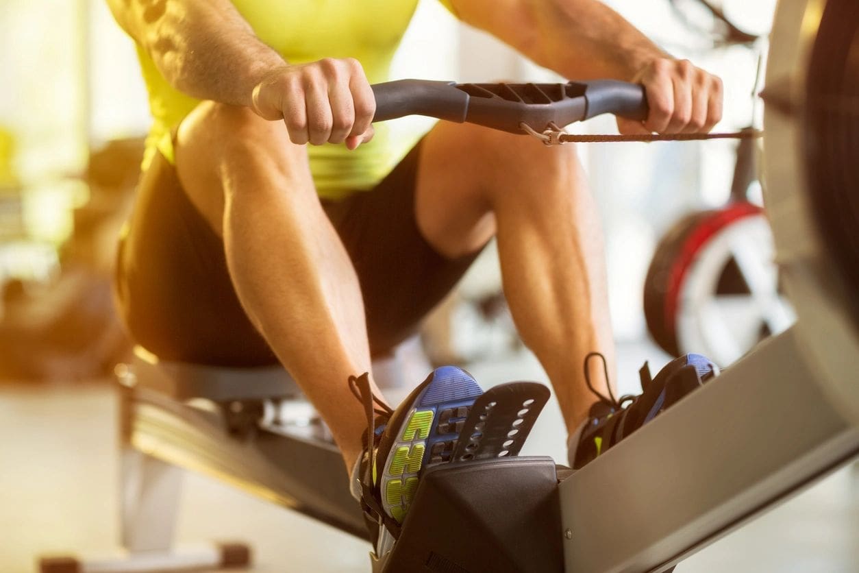 A man is riding on the rowing machine