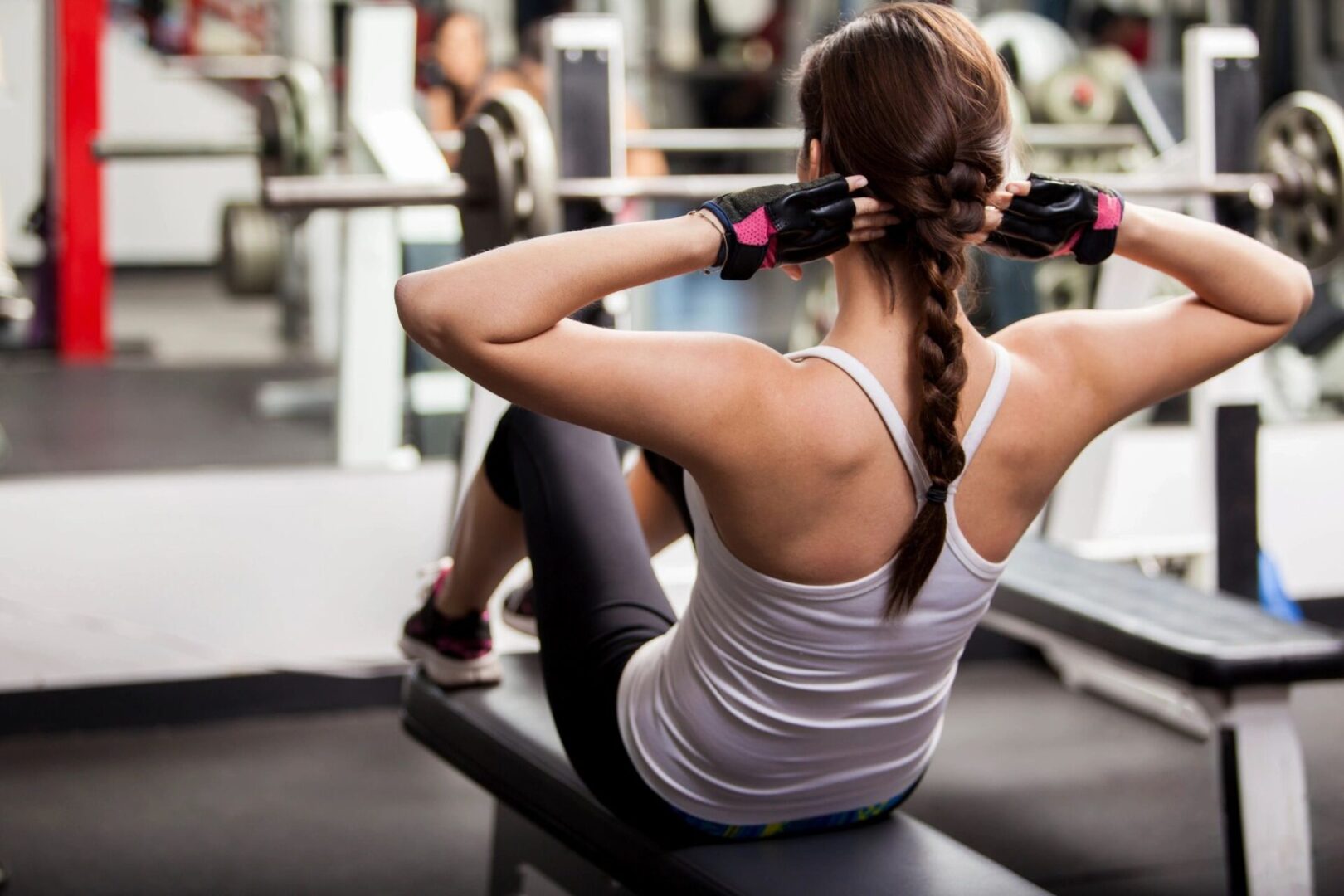 A woman is sitting on the bench in the gym